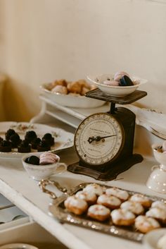 an assortment of pastries and desserts on a table with a clock in the middle