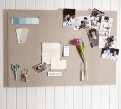 a bulletin board with pictures, photos and a pink flower in a vase next to a pair of scissors