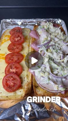 a sandwich with tomatoes, onions and cheese on it is sitting on tin foil next to another sandwich