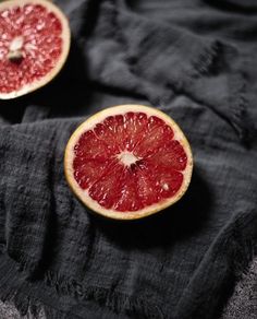 two grapefruits cut in half on a black cloth