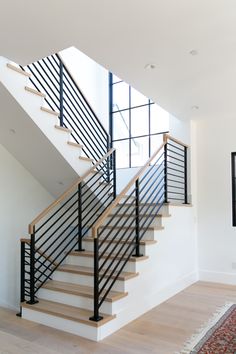 a white staircase with black railing and wooden handrails in a modern style home