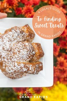 a white plate topped with powdered sugar covered pastry on top of a flower bed