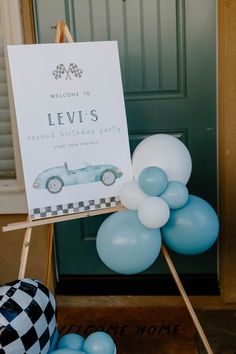 a welcome sign and balloons in front of a door with a checkerboard theme