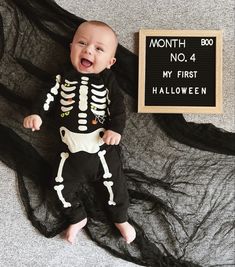 a baby in a skeleton costume next to a sign that says, month no 4 my first halloween