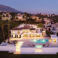 an aerial view of a home with pool and landscaping at dusk, surrounded by palm trees