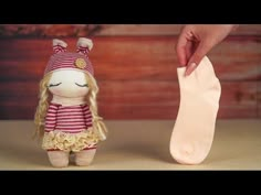 a small stuffed animal doll next to a large white sock on a table with wood planks in the background