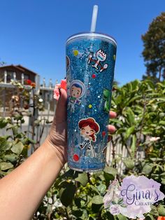 someone is holding up a cup with an image of princess and mickey mouse on it