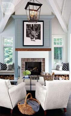 a living room with two white chairs and a fire place in the middle of it