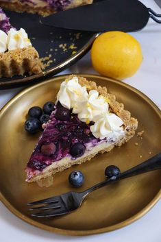 a piece of pie with blueberries and whipped cream on top sits on a gold plate