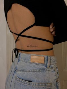 the back of a woman's stomach with a small tattoo on her left side