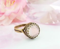 "This pink gemstone ring is made with a 10mm smooth, round genuine rose quartz cabochon and is set in your choice of lovely Victorian-style crown bezel in either antiqued bronze or antiqued silver. This adjustable ring will fit just about any finger and makes a great pink birthstone jewelry gift for her. Thank you for looking. - Shop Gemsicles, an Etsy boutique with hundreds of sparkly items for weddings, gifts and just because. Our original jewelry designs feature gemstones, Swarovski® crystals Formal Pink Rose Quartz Jewelry, Round Rose Quartz Birthstone Jewelry, Formal Rose Quartz Gemstone Jewelry, Pink Cabochon Jewelry For Wedding, Pink Cabochon Jewelry For Anniversary, Round Rose Quartz Promise Ring, Pink Cabochon Wedding Jewelry, Classic Pink Cabochon Jewelry, Adjustable Pink Moonstone Round Ring