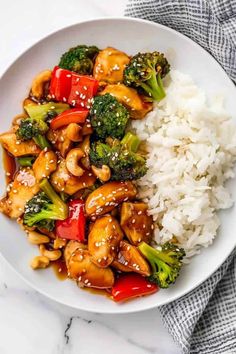 a white plate topped with chicken and broccoli covered in sauce next to rice