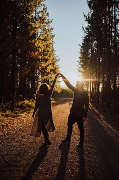 two people standing in the middle of a road holding their hands up to each other