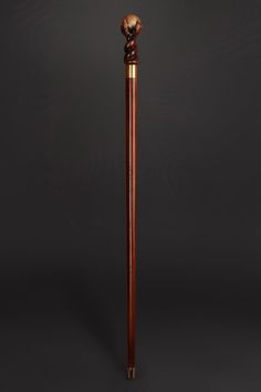 a wooden stick with a carved head on it's end and a metal handle