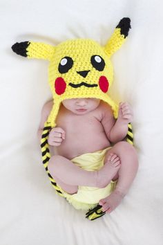 a baby wearing a pikachu hat while laying on top of a white blanket