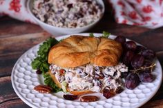 a chicken salad sandwich on a croissant with grapes and pecans