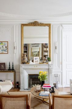 a living room filled with furniture and a fire place under a mirror on the wall