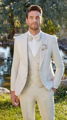 a man in a white suit and bow tie posing for a photo with his hands in his pockets