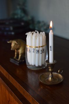 two candles sitting on top of a wooden table next to a small elephant figurine