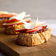 two pieces of bread with apple slices and cheese on them sitting on a cutting board