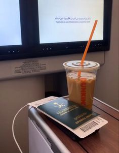 a drink with an orange straw sitting on top of a table next to a computer monitor