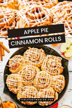 apple pie cinnamon rolls in a cast iron skillet on a table with apples and cinnamon sticks