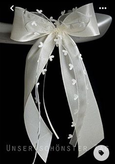 a white ribbon tied to the back of a chair with flowers and leaves on it