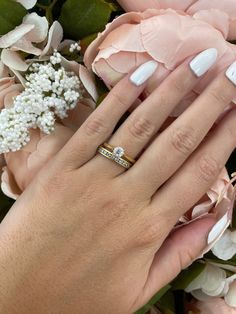 a woman's hand with white manicured nails holding a bouquet of flowers