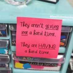 a pink sticky note attached to a blue drawer with plastic bins filled with files