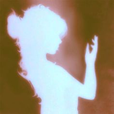 the silhouette of a woman holding a cell phone up to her ear and looking down