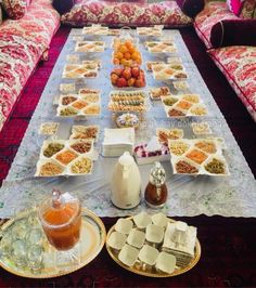 a table filled with lots of food on top of a red carpeted floor next to couches