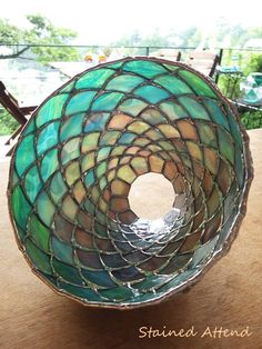 a stained glass bowl sitting on top of a wooden table