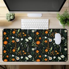 an overhead view of a computer keyboard and mouse on a desk with flowers, leaves and plants