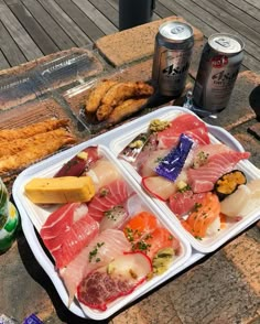 two trays filled with different types of food next to cans of soda and fish