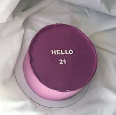 a pink cake with the words hello 21 on it is sitting on a white sheet