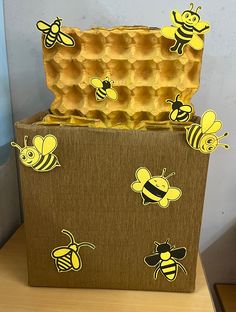 a cardboard box filled with honeybees on top of a wooden table next to a wall