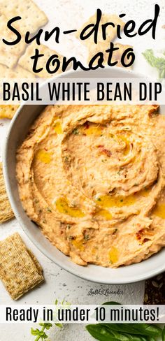 sun dried tomato basil white bean dip in a bowl with crackers on the side