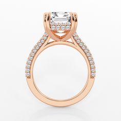 a rose gold engagement ring with an emerald center stone surrounded by small round brilliant cut diamonds