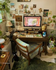 a desk with a computer on top of it in a room filled with pictures and plants