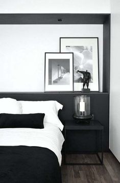 a black and white bedroom with pictures on the wall above the bed, along with candles