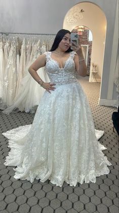 a woman is taking a selfie in her wedding dress while she stands next to some dresses