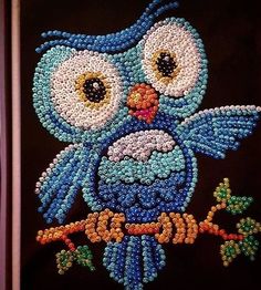 an owl is made out of beads on a black background, and it appears to be beaded