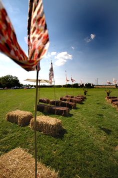 an open field with hay bales and flags