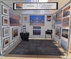 a white tent with pictures on the wall and black table cloths in front of it