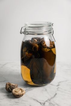 a glass jar filled with food sitting on top of a marble counter next to nuts