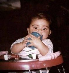 a baby sitting in a high chair holding a cup