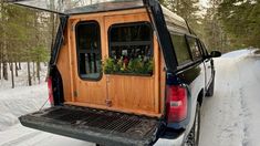 the back end of a pickup truck with an open window and flower box in the bed