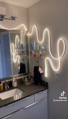 a bathroom with a sink, mirror and lights on the wall above it's counter