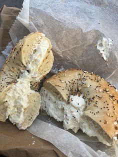 two bagels with cream cheese and sprinkles on them sitting on wax paper