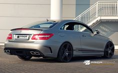 the rear end of a silver car parked in front of a white building with stairs